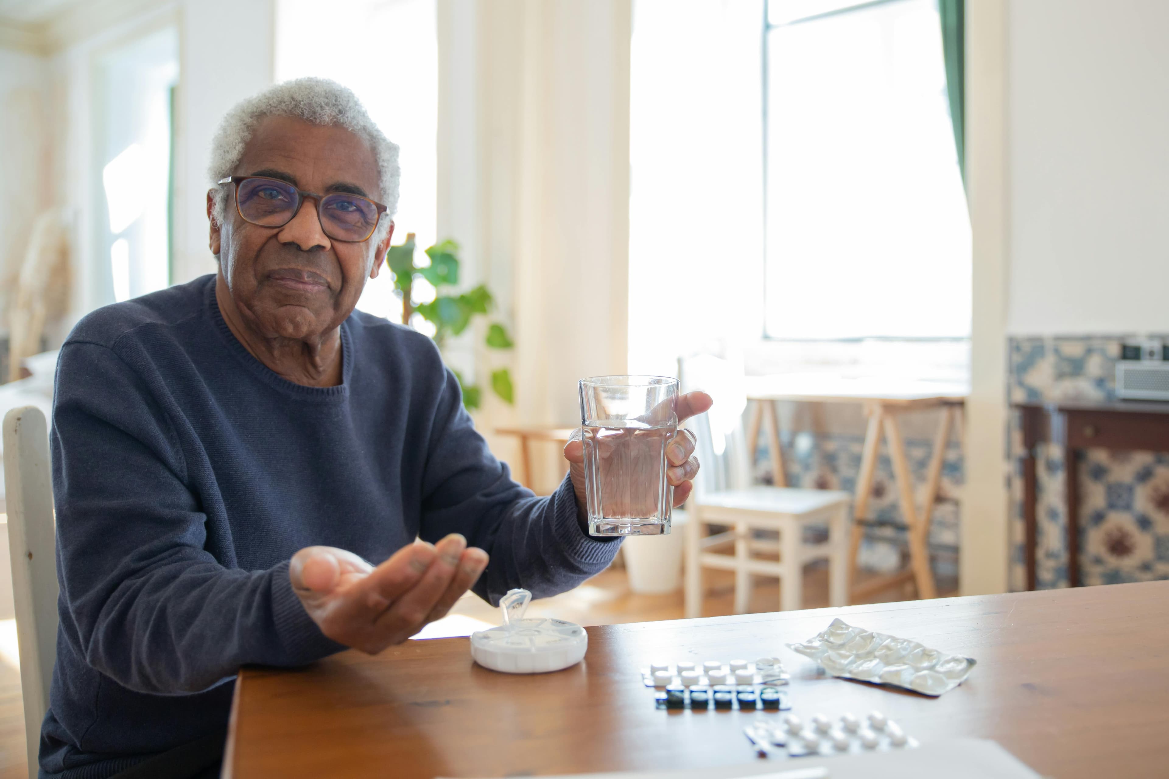 A man sitting at a table taking pills