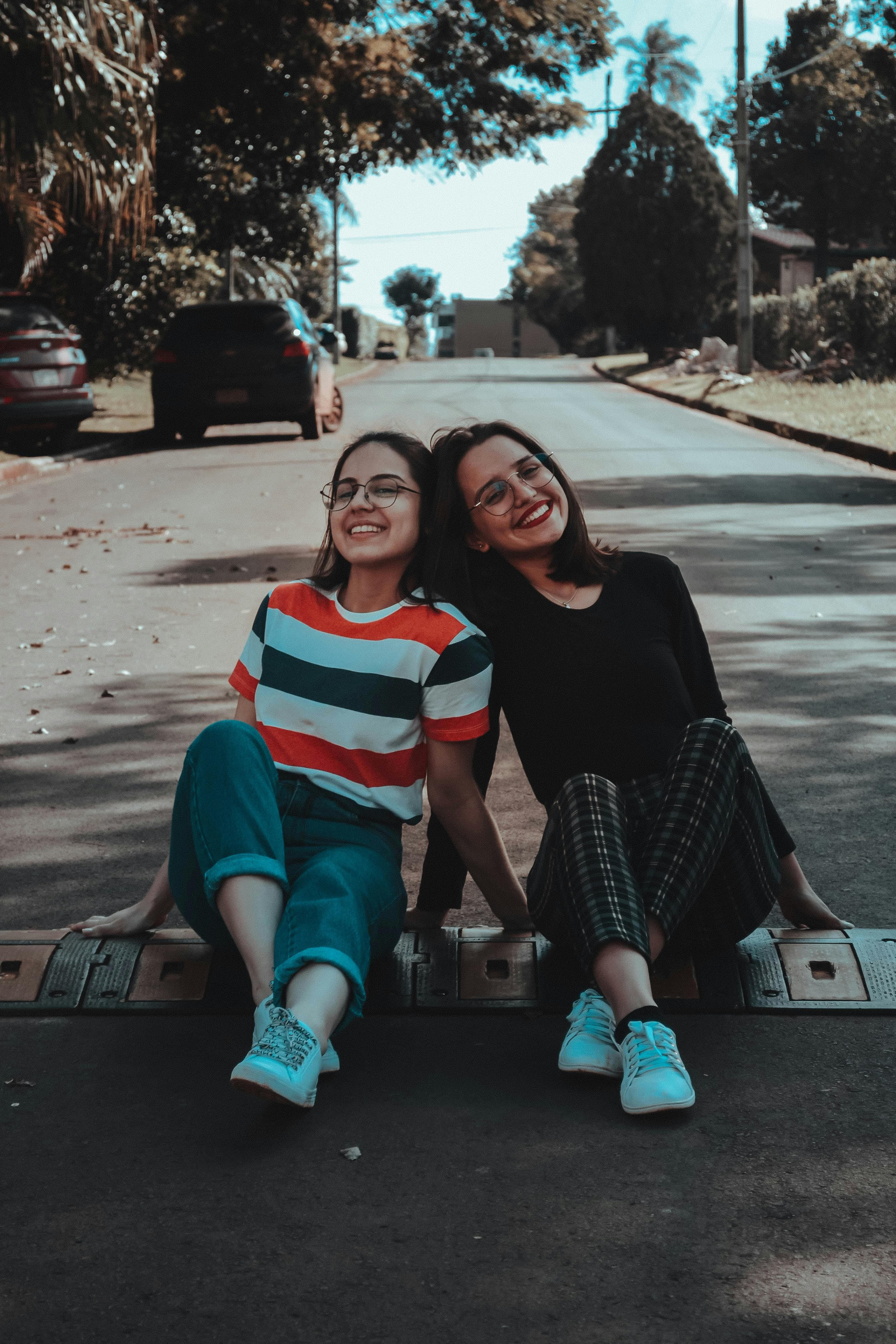 Two young women sitting on a speed bump