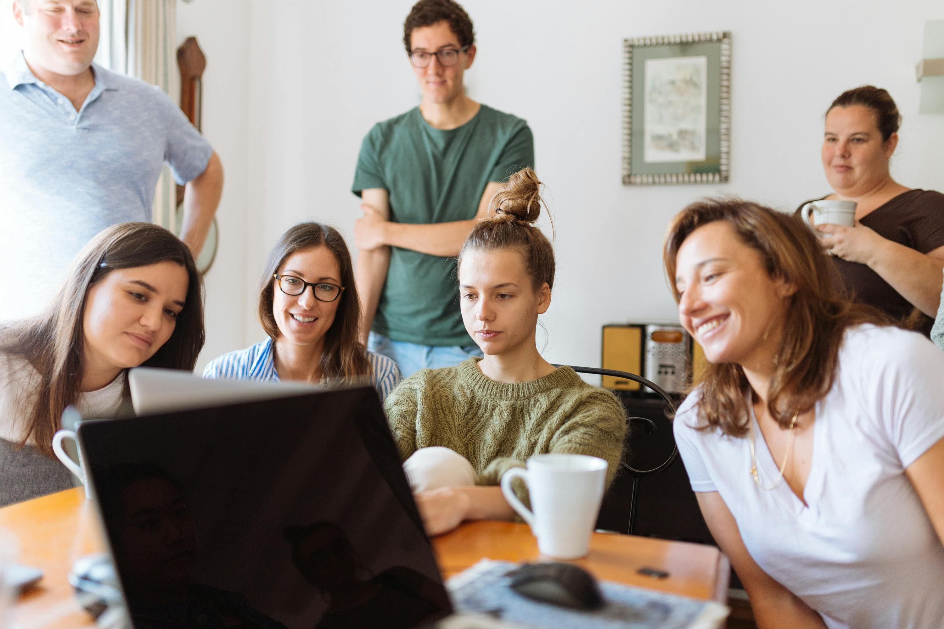 Group of people gathered around a computer