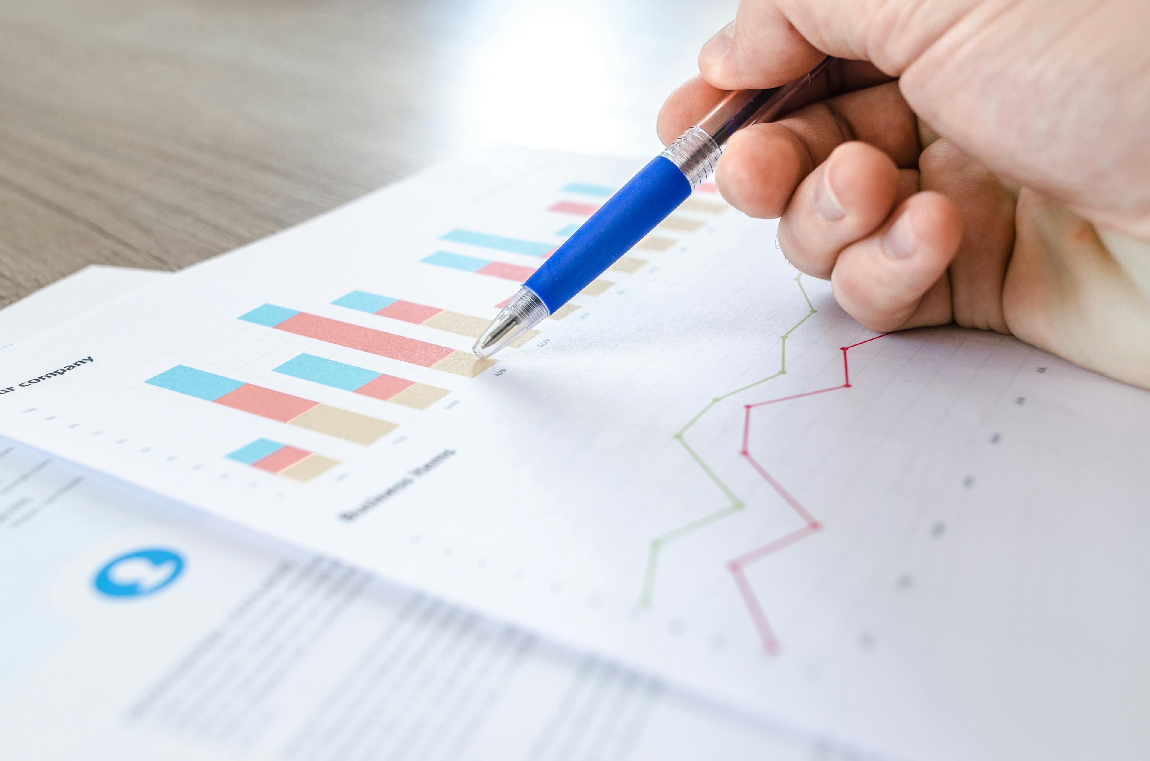 A person reviewing piece of paper with charts and statistics