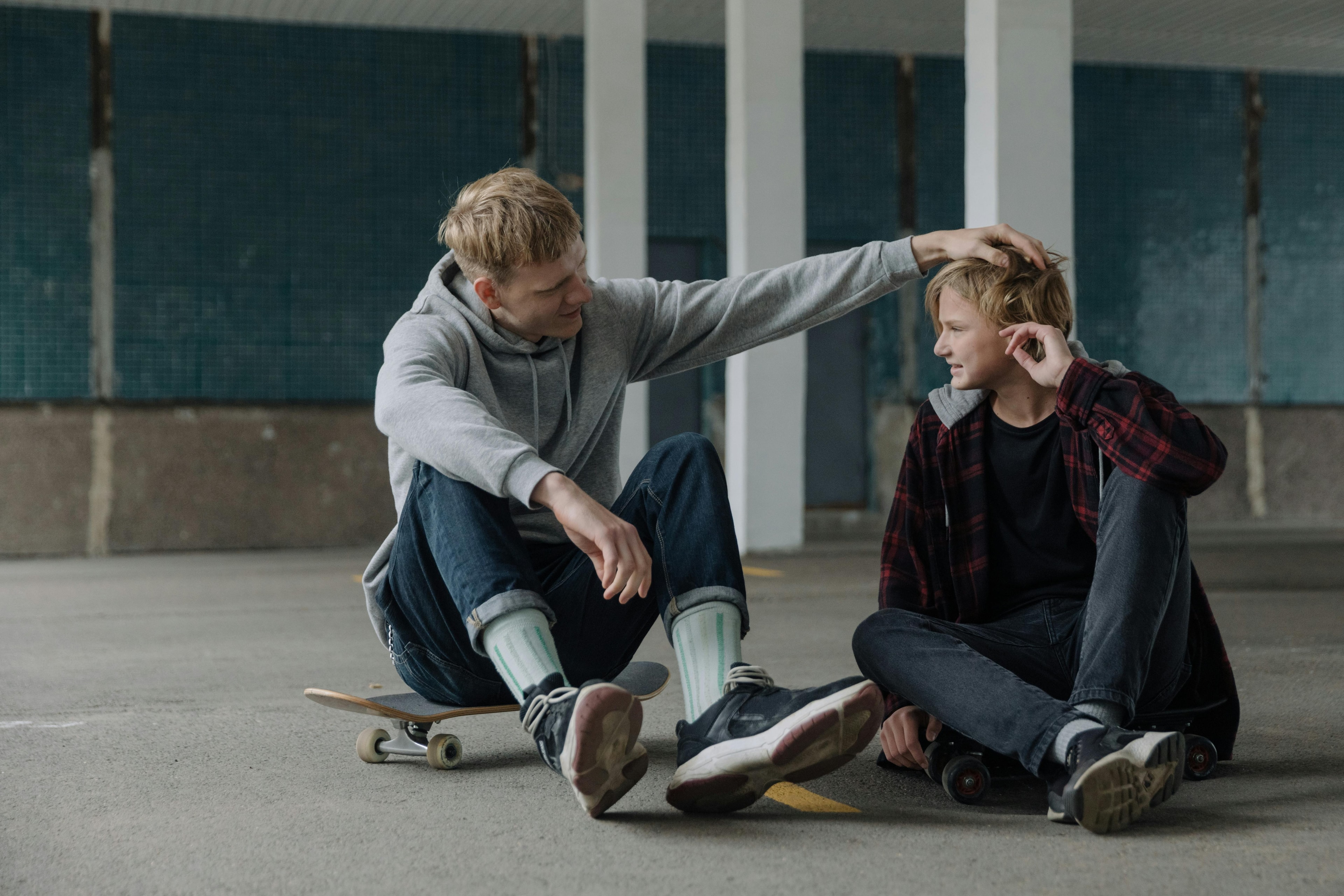 Two skateboarders sitting down on the pavement