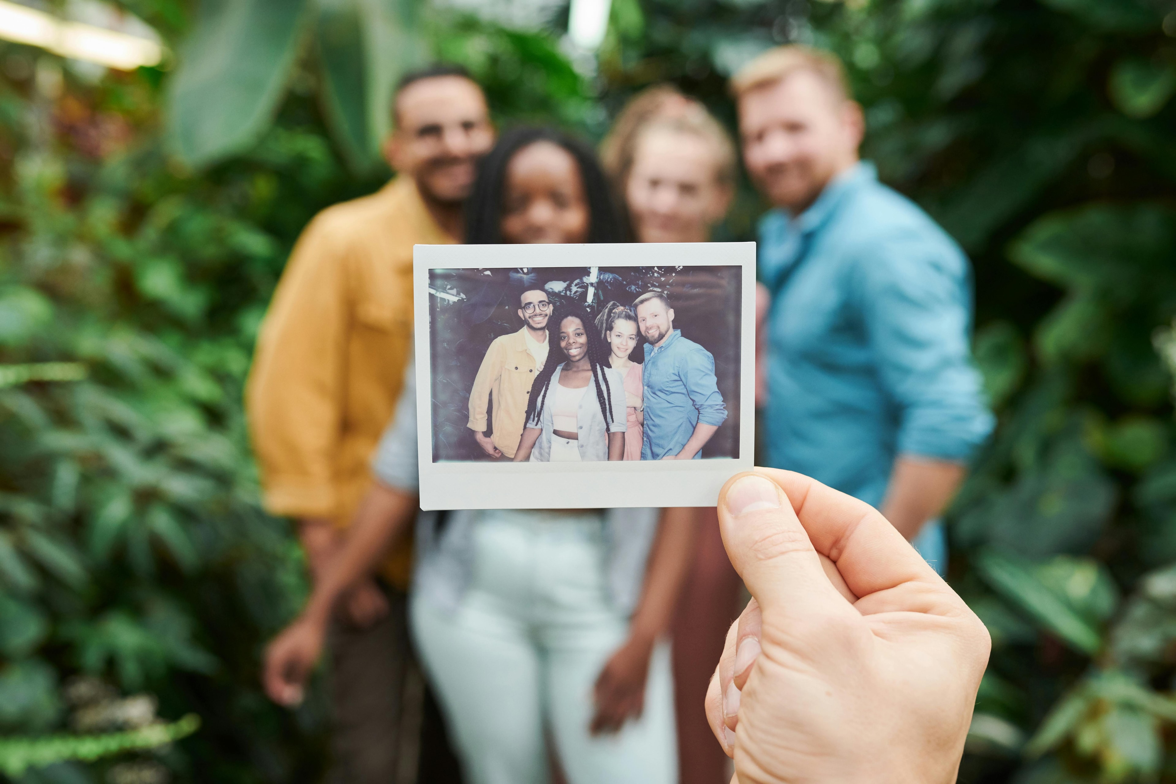 A hand holding a picture up in front of the same people