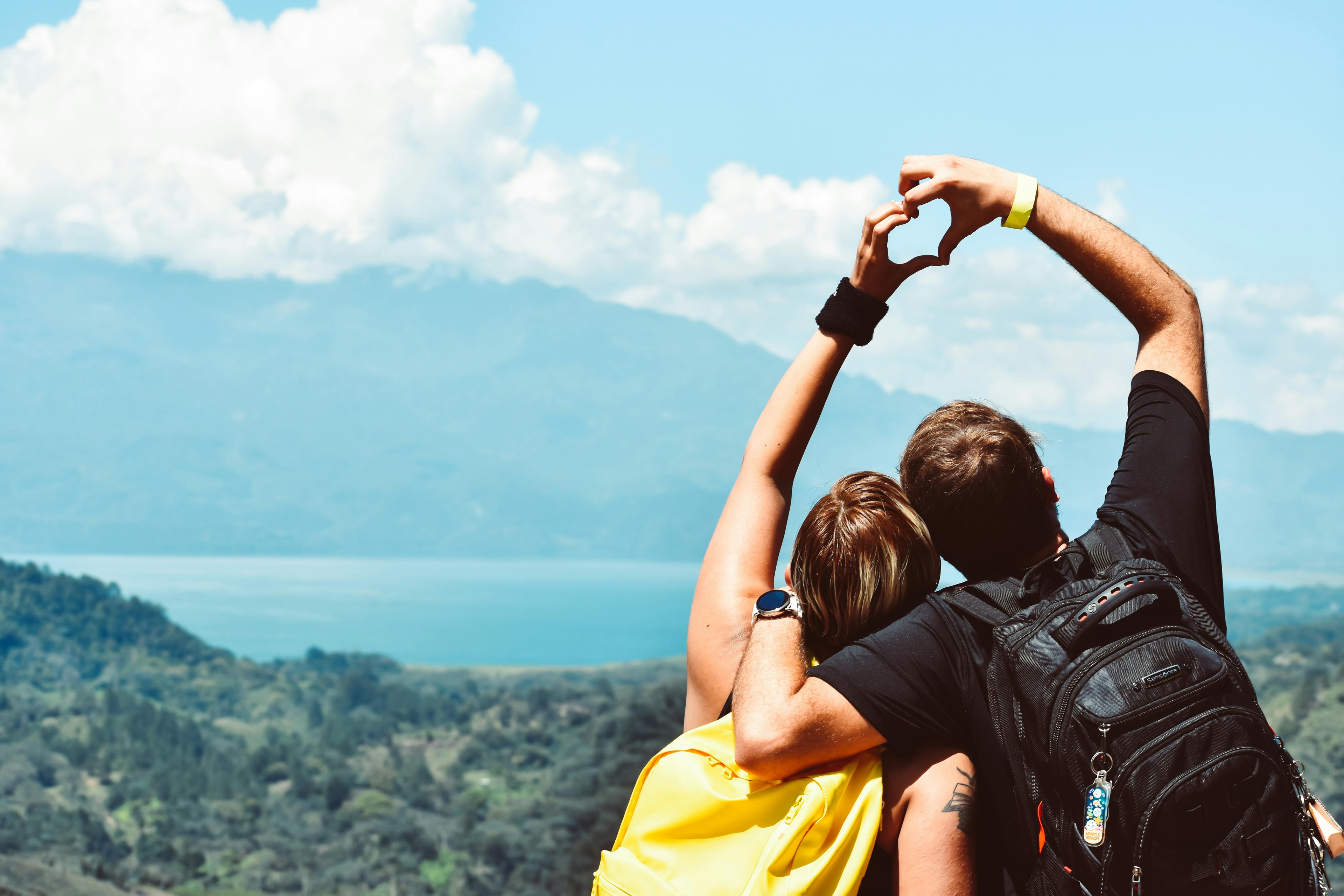 Two people making a heart with their hands while on a hike