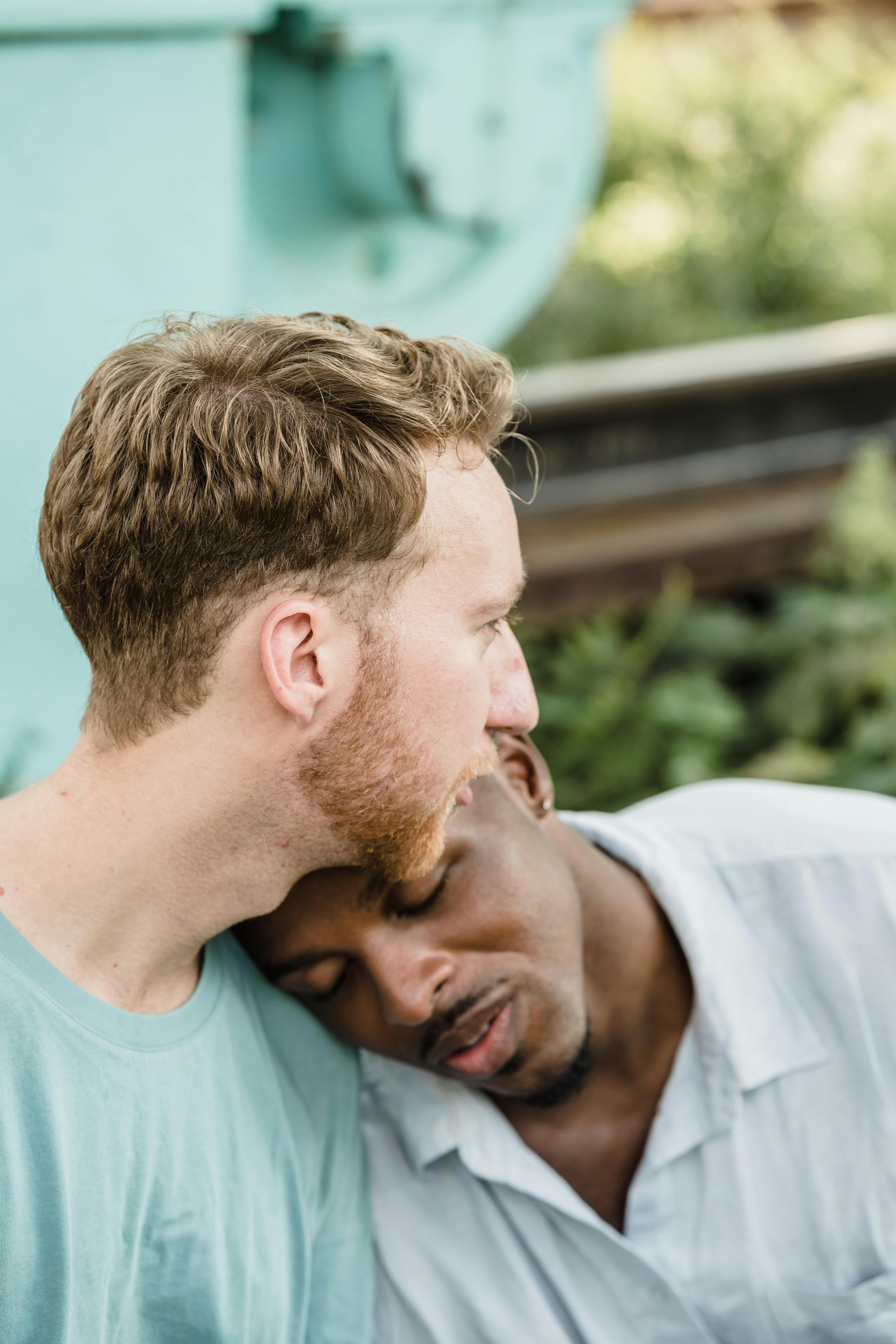 A man with his head on the shoulder of another